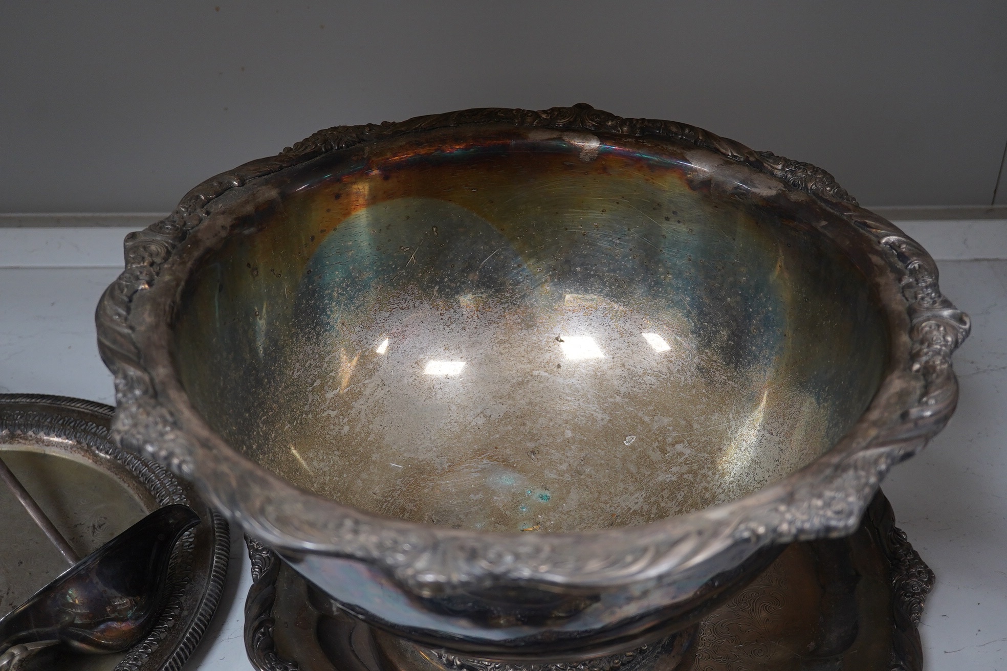 A collection of silver plate comprising large punchbowl, three plated ladles and three plated trays, punchbowl 43cm diameter. Condition - fair, worn